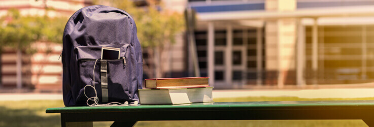 Backpack and books on bench with basketball to side