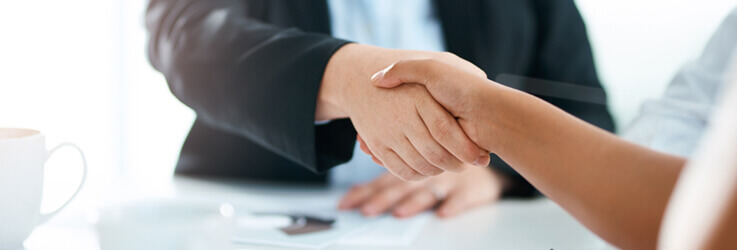Business people shaking hands with paperwork on desk